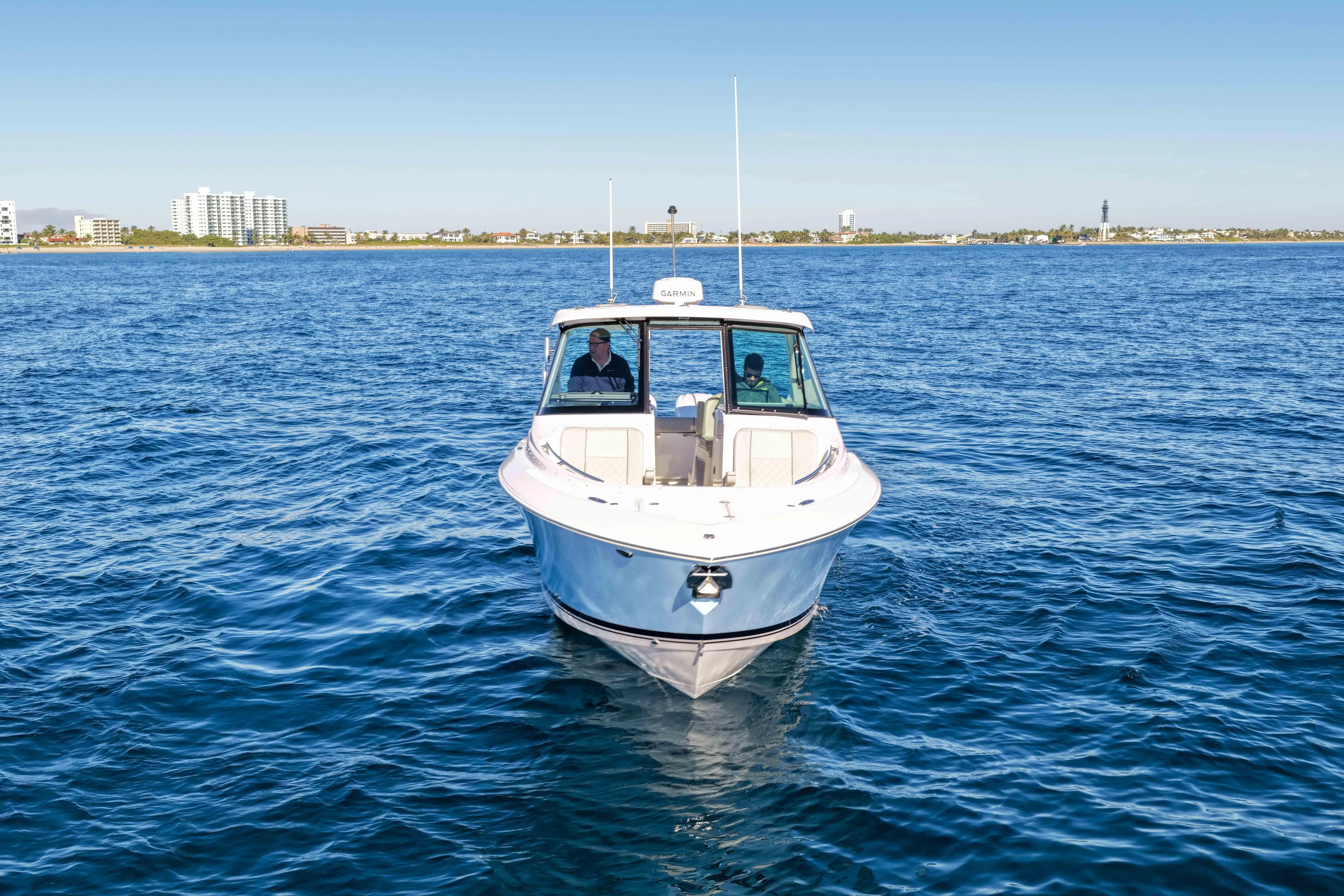 Endeavor Yacht Photos Pics 2023 Pursuit DC 295 Dual Console boat on open water, with city skyline in background.