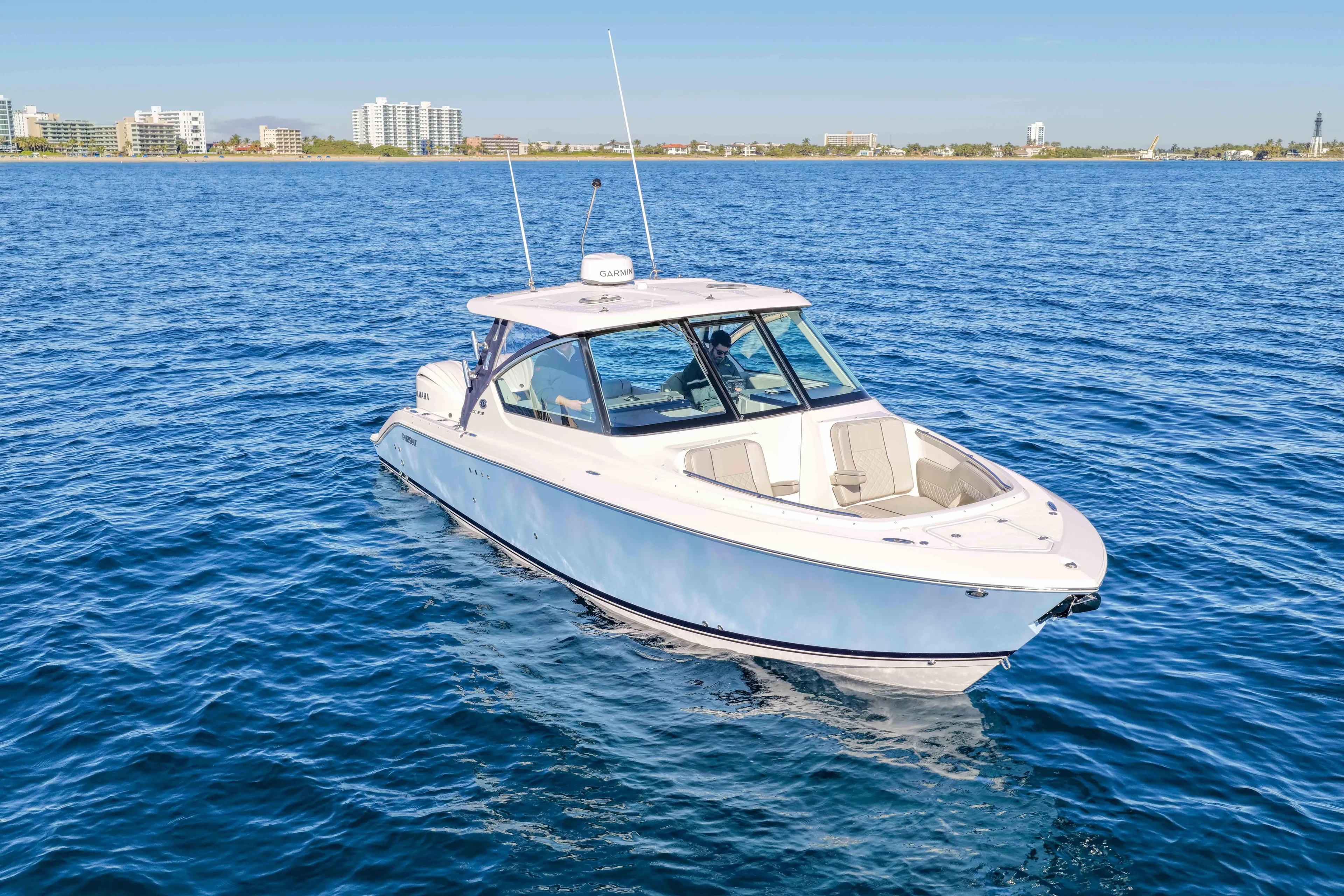 Endeavor Yacht Photos Pics 2023 Pursuit DC 295 Dual Console boat on open water, near coastal cityscape.