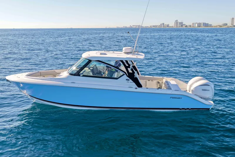 Endeavor Yacht Photos Pics 2023 Pursuit DC 295 Dual Console boat on open water, city skyline in background.