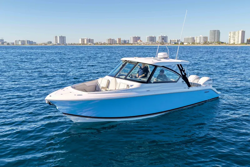 Endeavor Yacht Photos Pics 2023 Pursuit DC 295 Dual Console boat cruising on open water near city skyline.