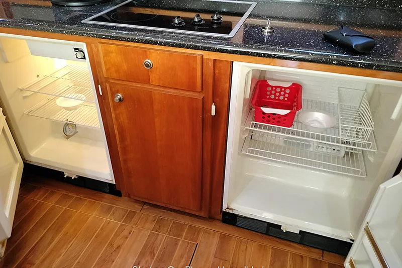 No Name Yacht Photos Pics Kitchen area of 2006 Navigator 5400 with open refrigerators and wooden cabinetry.