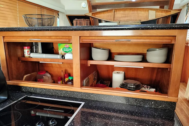 No Name Yacht Photos Pics Wooden kitchen cabinets in a 2006 Navigator 5400, with dishes and pantry items.