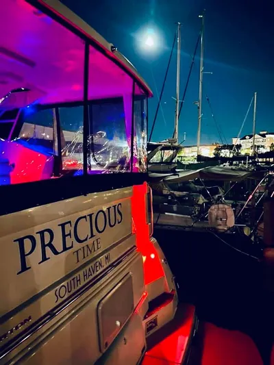 Precious Time Yacht Photos Pics 1998 Silverton 392 Motor Yacht docked at night, illuminated by colorful lights.