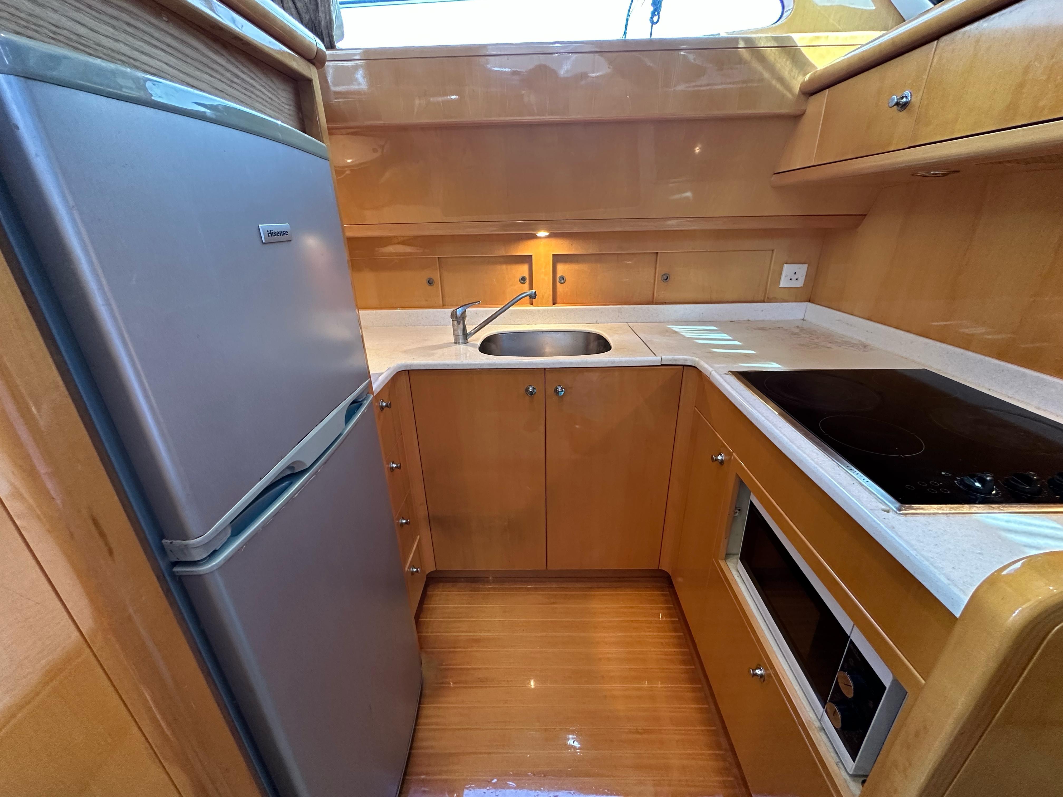 Compact kitchen in a 2005 Ruby 45 yacht with fridge, sink, and stove.