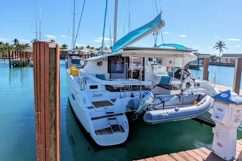 Imany Yacht Photos Pics 2012 Fountaine Pajot Lipari catamaran docked in a sunny marina with inflatable dinghy.