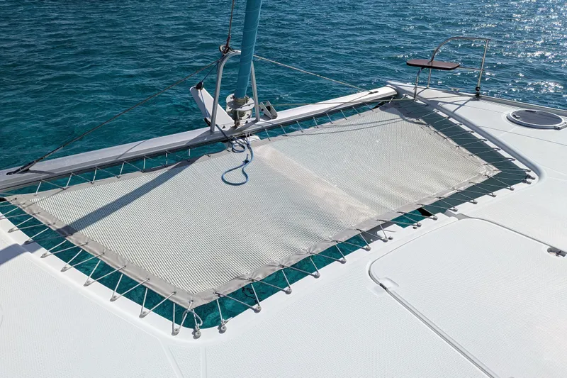 Imany Yacht Photos Pics 2012 Fountaine Pajot Lipari catamaran deck with netting over clear blue water.