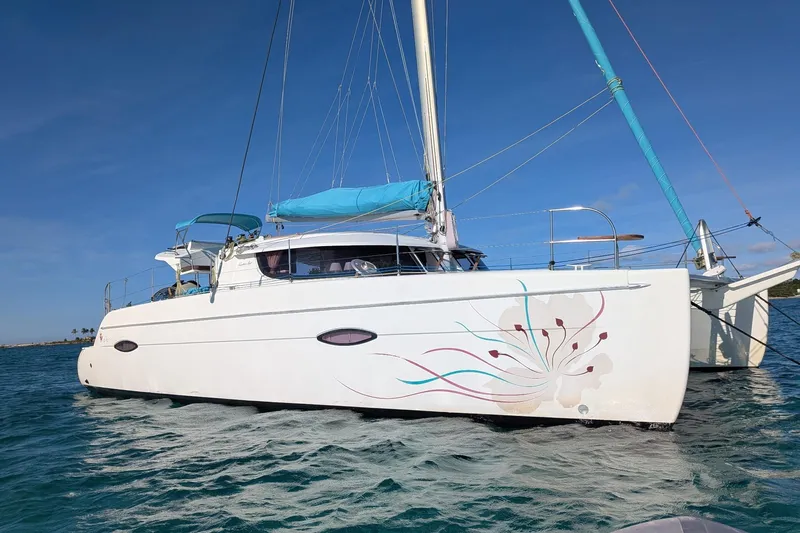 Imany Yacht Photos Pics 2012 Fountaine Pajot Lipari catamaran with decorative hull design on calm water.