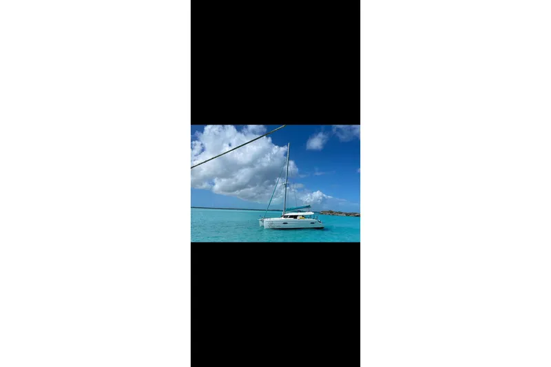 Imany Yacht Photos Pics 2012 Fountaine Pajot Lipari catamaran sailing on clear turquoise waters under a blue sky.