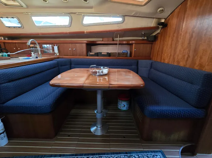 Scuba Duo Yacht Photos Pics Cozy interior of 2004 Hunter 41 AC sailboat with wooden table and blue seating.