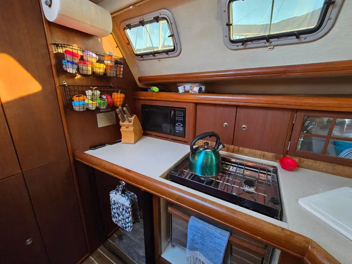 Scuba Duo Yacht Photos Pics Cozy 2004 Hunter 41 AC sailboat kitchen with stove, microwave, and colorful storage baskets.