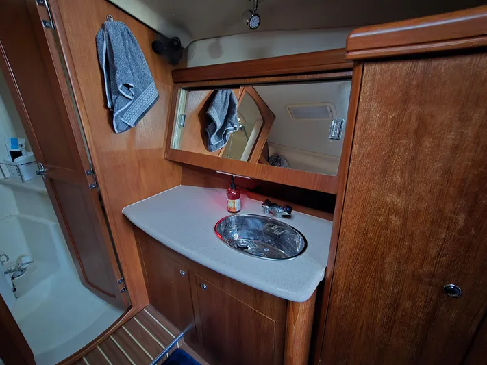 Scuba Duo Yacht Photos Pics 2004 Hunter 41 AC yacht bathroom with wooden cabinetry, mirror, and stainless steel sink.