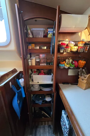 Scuba Duo Yacht Photos Pics Wooden pantry in a 2004 Hunter 41 AC sailboat, stocked with kitchen essentials.