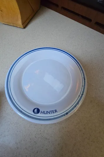 Scuba Duo Yacht Photos Pics White Hunter plate with blue trim on a countertop, featuring the Hunter logo.