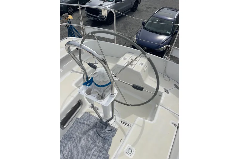 Spray Yacht Photos Pics Steering wheel of a 2002 Tartan 37 sailboat, docked with cars nearby.