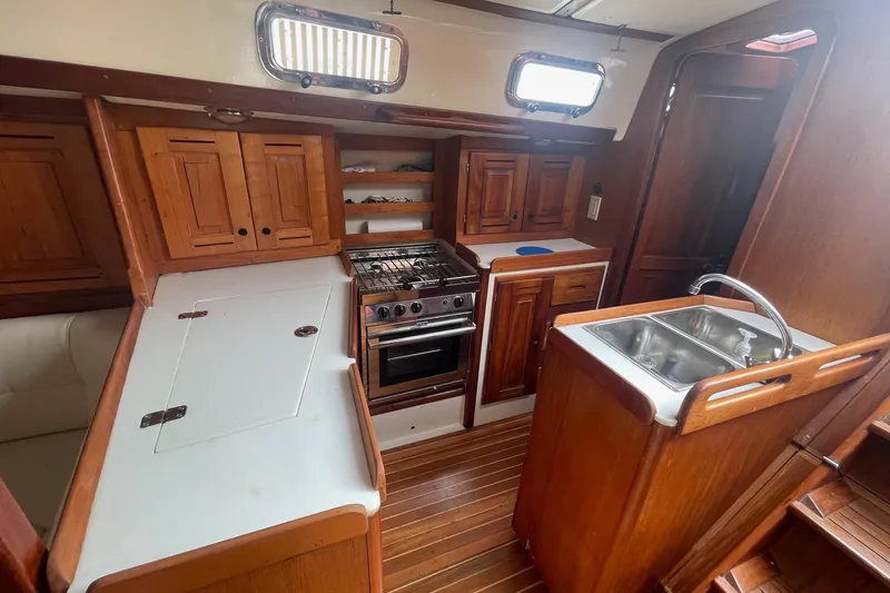 Spray Yacht Photos Pics Interior of 2002 Tartan 37 sailboat kitchen with wooden cabinetry and stainless steel sink.
