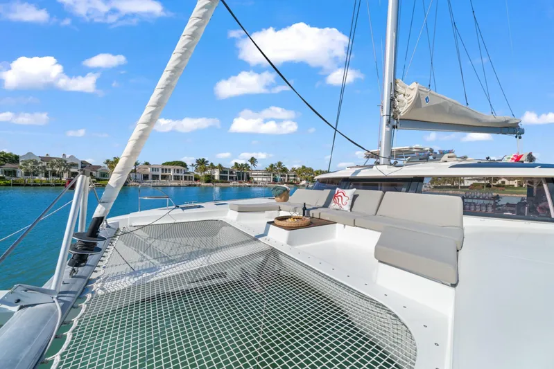 Halcyon Yacht Photos Pics 2024 Fountaine Pajot Aura 51 Catamaran on serene blue water, featuring spacious deck seating.