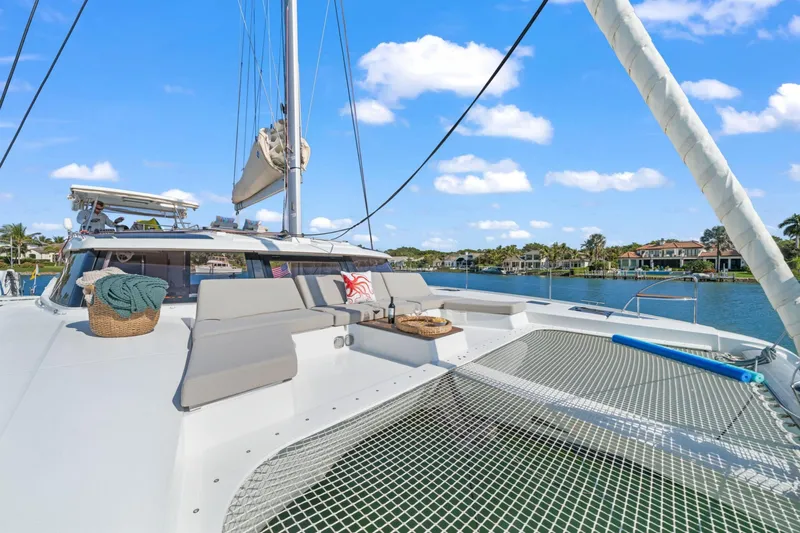 Halcyon Yacht Photos Pics 2024 Fountaine Pajot Aura 51 Catamaran on tranquil water, featuring spacious deck and seating.