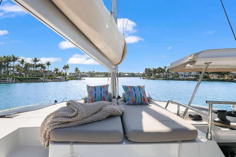 Halcyon Yacht Photos Pics 2024 Fountaine Pajot Aura 51 Catamaran deck with cushions and scenic waterfront view.