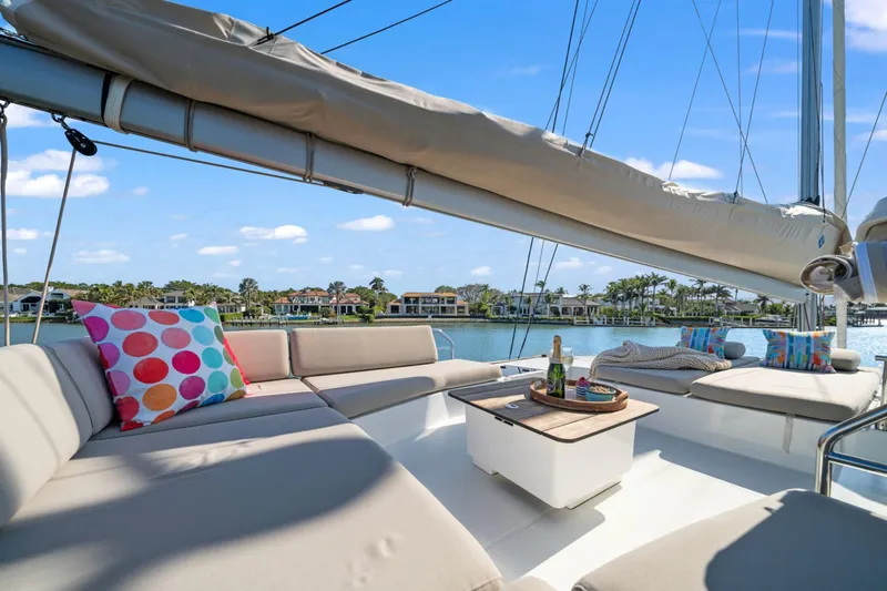 Halcyon Yacht Photos Pics 2024 Fountaine Pajot Aura 51 Catamaran deck with colorful cushions and scenic waterfront view.