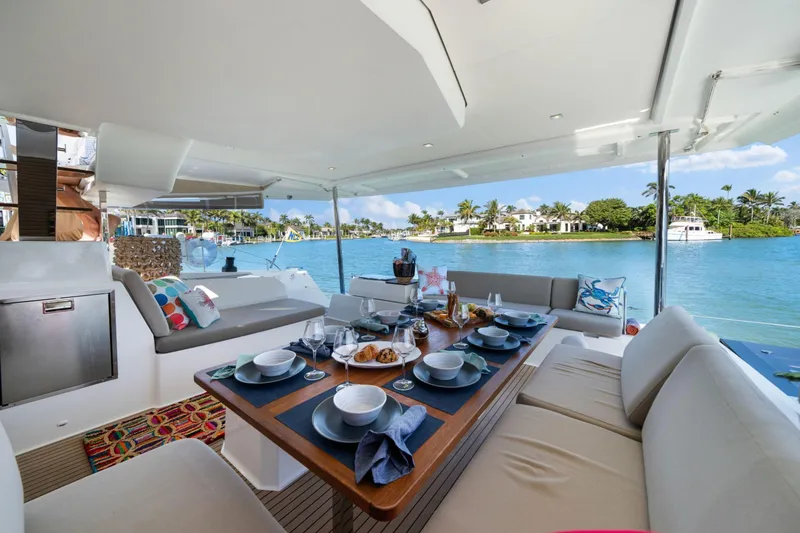 Halcyon Yacht Photos Pics Luxurious 2024 Fountaine Pajot Aura 51 Catamaran with elegant dining setup and scenic waterfront view.