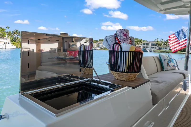 Halcyon Yacht Photos Pics 2024 Fountaine Pajot Aura 51 Catamaran deck with seating, basket, and American flag.