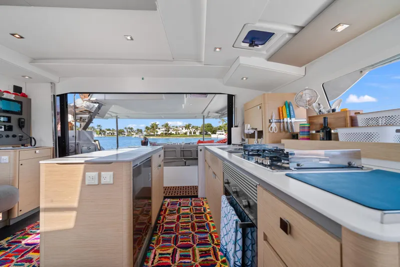 Halcyon Yacht Photos Pics Modern kitchen interior of 2024 Fountaine Pajot Aura 51 Catamaran with vibrant decor and ocean view.