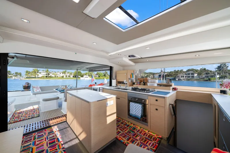 Halcyon Yacht Photos Pics Luxurious interior of 2024 Fountaine Pajot Aura 51 Catamaran with modern kitchen and scenic views.
