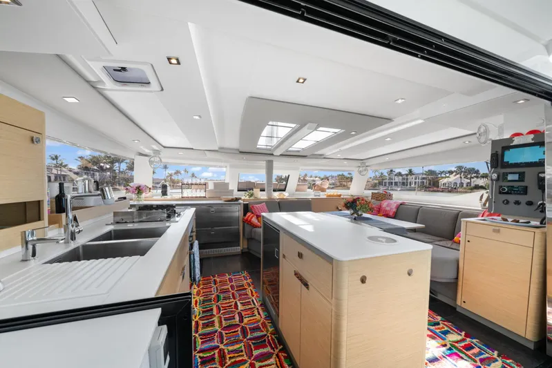 Halcyon Yacht Photos Pics Luxurious interior of 2024 Fountaine Pajot Aura 51 Catamaran with modern kitchen and seating area.
