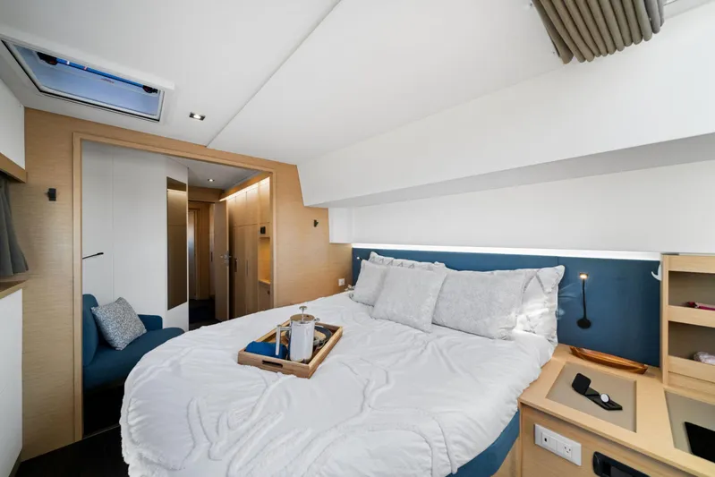 Halcyon Yacht Photos Pics Luxurious bedroom interior of 2024 Fountaine Pajot Aura 51 Catamaran, featuring modern design and cozy bedding.