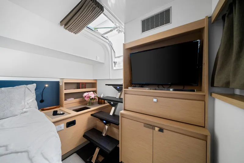 Halcyon Yacht Photos Pics 2024 Fountaine Pajot Aura 51 Catamaran interior cabin with TV, bed, and storage.