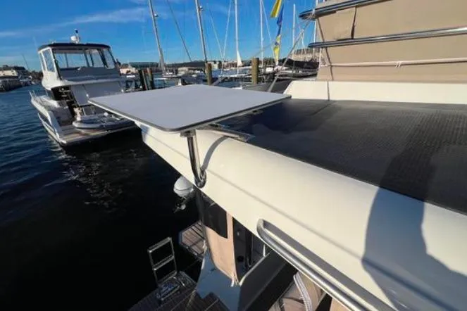 Halcyon Yacht Photos Pics 2024 Fountaine Pajot Aura 51 Catamaran, docked with extended table, sunny marina setting.