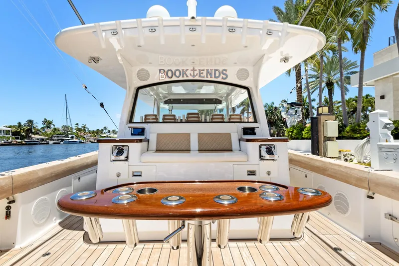 Book Ends Yacht Photos Pics 2021 HCB Estrella yacht with luxurious seating and polished wood table, docked by palm trees.