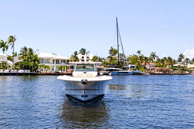 Book Ends Yacht Photos Pics 2021 HCB Estrella boat on a sunny waterfront with palm trees and houses.