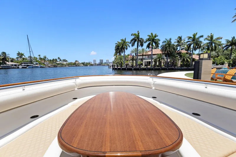 Book Ends Yacht Photos Pics 2021 HCB Estrella yacht with wooden deck, cruising along a scenic waterfront with palm trees.
