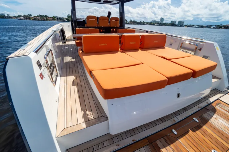  Yacht Photos Pics 2020 Fjord 44 Open yacht with orange sunbeds on a wooden deck, docked by the water.