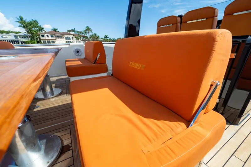  Yacht Photos Pics Orange seating on 2020 Fjord 44 Open yacht deck, with wooden table and coastal view.