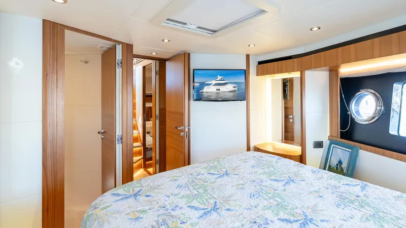 Just Joanne Yacht Photos Pics Luxurious bedroom interior of 2019 Absolute NAVETTA 58 yacht with wooden accents and porthole window.