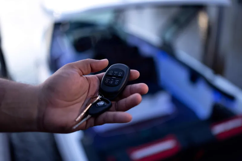  Yacht Photos Pics Hand holding keys for 2026 Monterey Elite 30 OB boat, blurred background.