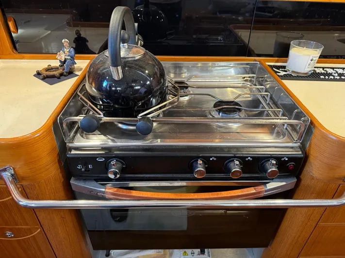  Yacht Photos Pics Stove with kettle in 2004 X-Yachts X 46 galley, featuring wooden cabinetry.