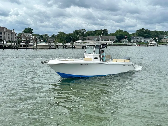  Yacht Photos Pics 2022 Release 240RX boat cruising on a calm waterfront with houses in the background.