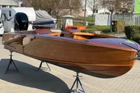 2024 Custom Bowrider boat with sleek wooden finish on display outdoors.