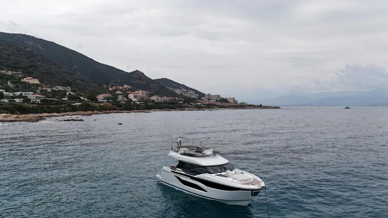 Prestige F4.9 Yacht Photos Pics Luxury Prestige F4 yacht on serene coastal waters, 2025 model, with scenic hillside backdrop.