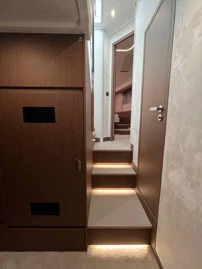 Prestige F4.9 Yacht Photos Pics Interior of 2025 Prestige F4 yacht with modern wood paneling and illuminated stairs.