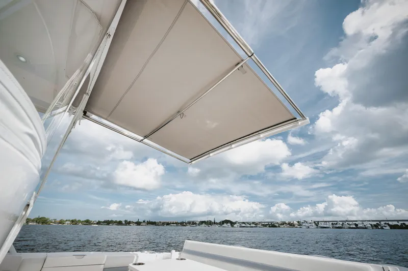  Yacht Photos Pics 2018 Intrepid 475 Sport Yacht with canopy, overlooking serene waters and cloudy sky.
