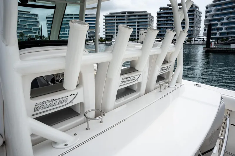  Yacht Photos Pics 2014 Boston Whaler 350 Outrage boat with rod holders, docked near modern buildings.