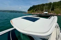 2020 Axopar 37 Cross Cabin with solar panel, cruising near a scenic coastline.