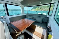 Interior of 2020 Axopar 37 Cross Cabin with seating and wooden table, ocean view.