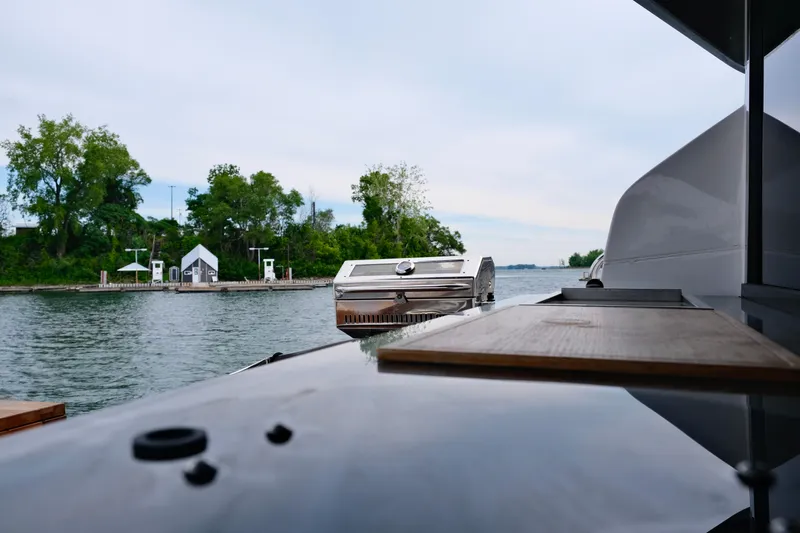  Yacht Photos Pics 2022 Sessa Marine Coupe 47 yacht with outdoor grill, docked by a scenic shoreline.