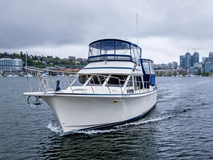 Bleu Fish Yacht Photos Pics 1988 Tollycraft 44 CPMY cruising on a calm, overcast waterway near urban skyline.