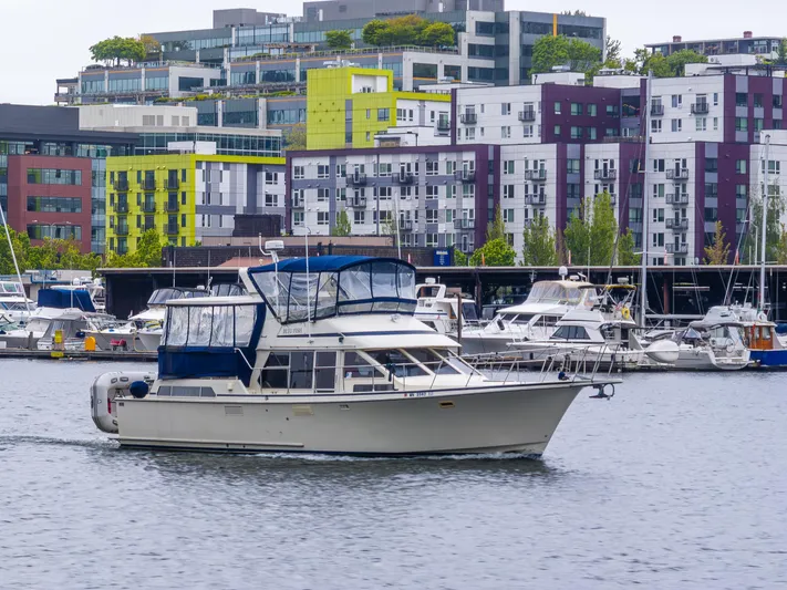 Bleu Fish Yacht Photos Pics 1988 Tollycraft 44 CPMY yacht cruising in urban marina with colorful buildings in background.